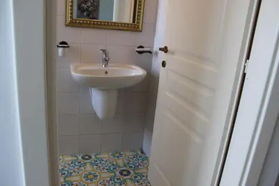a small bathroom with a sink and a mirror at Catarin Comfort Rooms in Castelluzzo