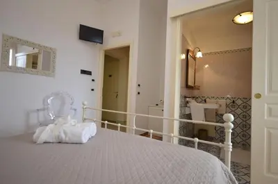 a bedroom with a white bed and a mirror at Catarin Comfort Rooms in Castelluzzo