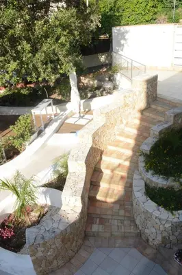 a stone path with a bench in a garden at I colori del mare in Macari