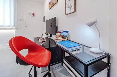 a red chair sitting next to a desk with a laptop at AL BAYDA in Palermo