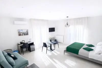 a white bedroom with a bed and a desk at Maqueda Suites in Palermo