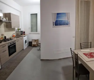 a kitchen with white walls and a table with chairs at ADRIANA SEAHOUSE in Balestrate