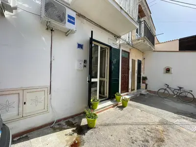 a white building with a green door and potted plants at Casa vacanze Baglio Barcellona Mondello in Palermo