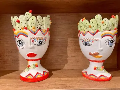 two vases with faces on them sitting on a table at Cortile Marconi Apartment in Palermo