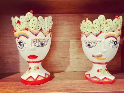 two vases with faces on them sitting on a table at Cortile Marconi Apartment in Palermo
