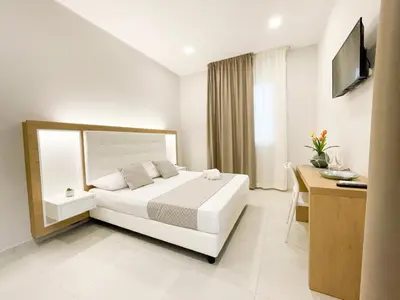 a bedroom with a bed and a desk and a television at Alba e Tramonto in San Vito lo Capo