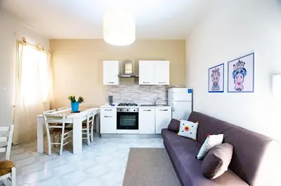 a living room with a couch and a kitchen at Le case di Sofia in Isola delle Femmine