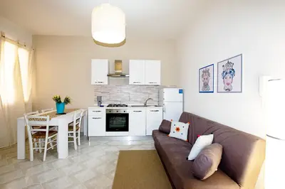 a living room with a couch and a kitchen at Le case di Sofia in Isola delle Femmine