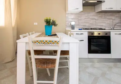 a kitchen with a white table with chairs and a stove at Le case di Sofia in Isola delle Femmine