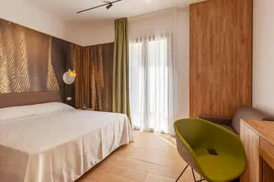 a bedroom with a bed and a green chair at LA DAMA in San Vito lo Capo