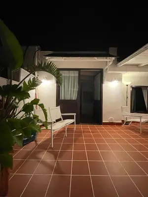 a patio with two white chairs and a tiled floor at Surfinia’s home in Palermo