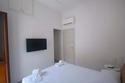 a white bedroom with a bed and a tv on the wall at GIADA in Castellammare del Golfo