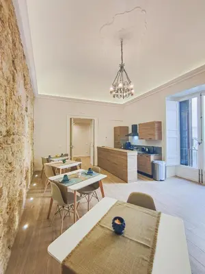 a living room with tables and chairs and a kitchen at Dimora Carella Ai 5Venti in Palermo