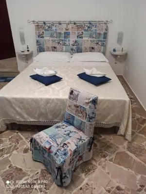 a bedroom with a bed and a chair with plates and napkins at NARDINA HOUSE in Castellammare del Golfo