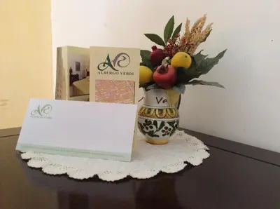 a table with a vase of fruit and a sign at Albergo Verdi in Palermo