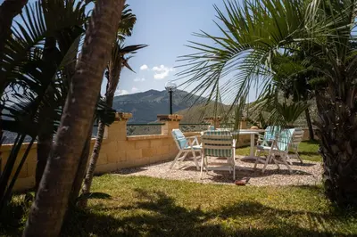 a patio with a table and chairs and palm trees at Villa vista mare con piscina privata a Mondello in Palermo