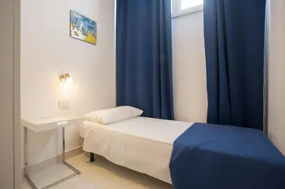 a bedroom with a bed and a sink and blue curtains at Mondello Suites FLH - Gorgonia in Mondello