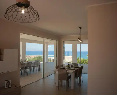 a dining room with a table and a view of the ocean at Villa Lombardo Luxury in Balestrate