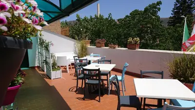 a patio with tables and chairs and purple flowers at Villa Scaduto Residence in Bagheria