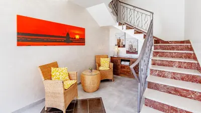 a staircase in a living room with chairs and a table at Hotel Piccolo Mondo in San Vito lo Capo