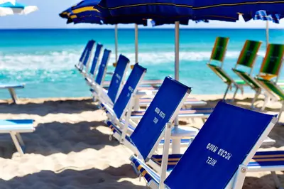 a group of chairs and umbrellas on a beach at Hotel Piccolo Mondo in San Vito lo Capo