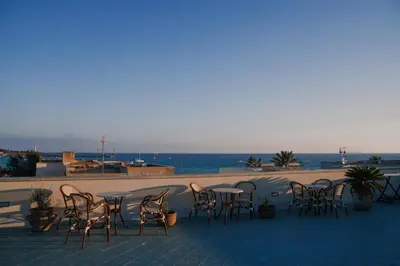 a group of chairs and tables on a patio overlooking the ocean at Hotel Piccolo Mondo in San Vito lo Capo