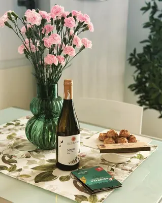 a bottle of wine on a table with a vase of flowers at Maison Opéra in Palermo