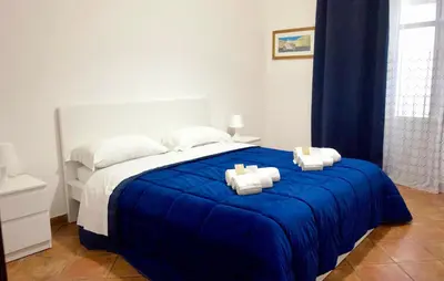 a bed with a blue blanket on top of it at Sikelia Apartment in Palermo