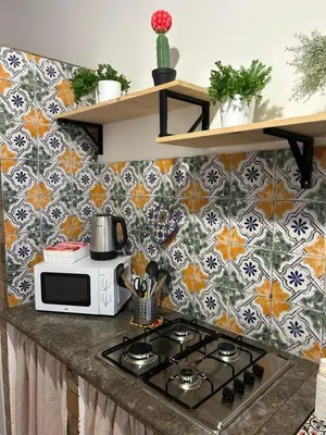 a kitchen with a stove and a tile wall at Sikelia Apartment in Palermo
