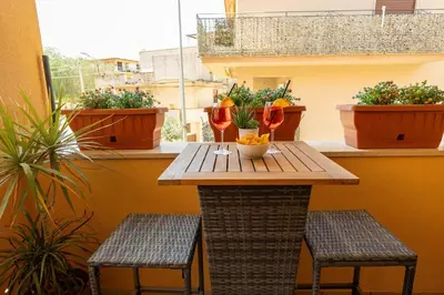 a table on a balcony with two chairs and plants at Sunset House in Balestrate