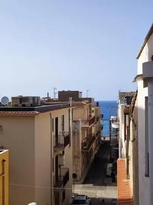 a city street with buildings and the ocean in the background at La Rosa Dei Venti in Castellammare del Golfo