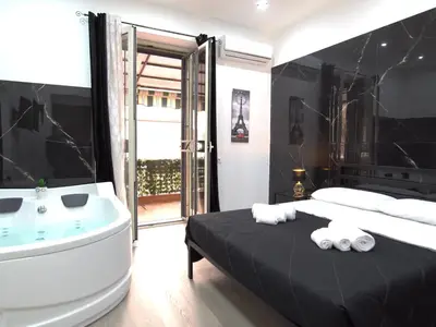 a bedroom with a tub and a bed with towels at Aliva suite LT in Palermo