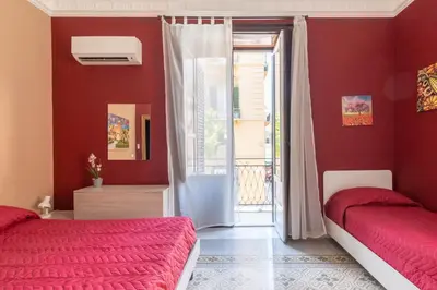 two beds in a room with red walls at Corner Rome 433 in Palermo