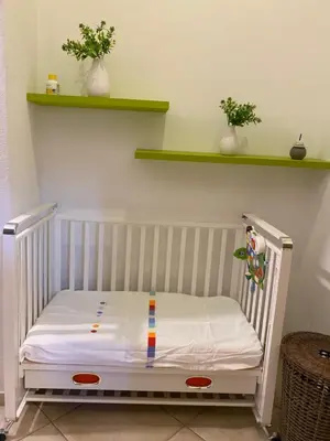 a crib in a room with two plants and shelves at Le_case_di_Antonella - your holiday in Sicilia in Castellammare del Golfo