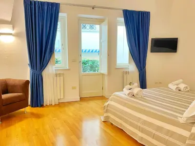 a bedroom with blue curtains and a bed and a chair at Giardino Segreto Luxury Home in Palermo