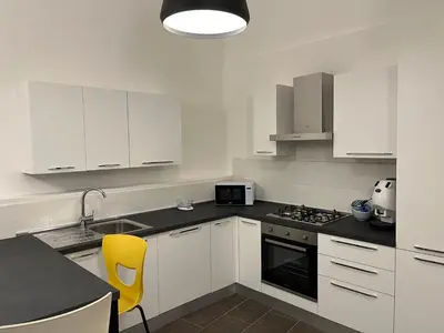 a kitchen with white cabinets and a yellow chair in it at Giardino Segreto Luxury Home in Palermo