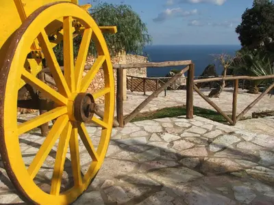 a yellow wagon wheel sitting next to a fence at Casale Corcella in Scopello