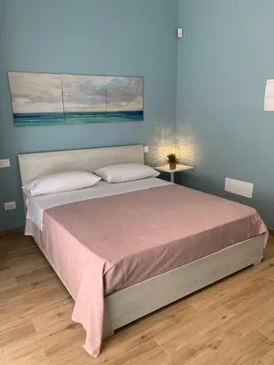 a bedroom with a large bed with a pink blanket at Denise Vacanze - Monolocali arredati in Bagheria