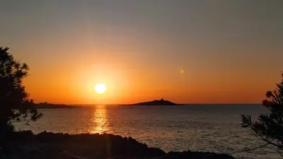 a sunset over the water with an island in the distance at Goccia del mare in Isola delle Femmine