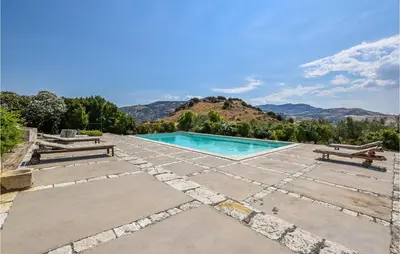 a swimming pool with a bench and mountains in the background at Acque Di Palermo in Roccapalumba