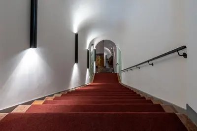 a red carpeted staircase in a building with lights at Suite Bellini 5 Apartment in Palermo