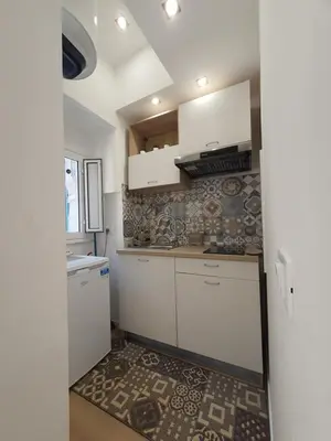 a kitchen with white cabinets and a tile wall at A casa di Claudia in Palermo