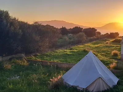 a tent in a field with the sunset in the background at Esmaraldas House of Love in Terrasini