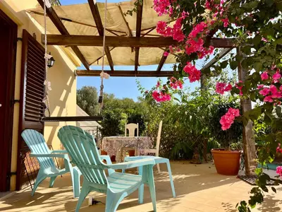 two chairs and a table on a patio with pink flowers at Esmaraldas House of Love in Terrasini