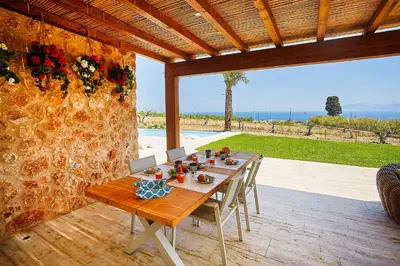 a wooden table and chairs on a patio at VILLA DEL BORGO con piscina e jacuzzi in Scopello