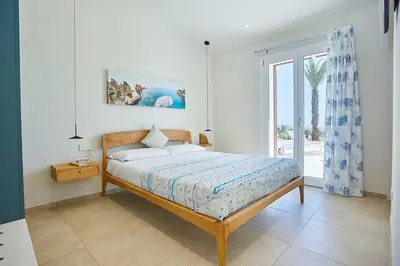 a bedroom with a bed and a large window at VILLA DEL BORGO con piscina e jacuzzi in Scopello