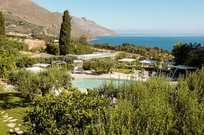 a resort with a swimming pool and the ocean at Hotel La Tavernetta in Scopello