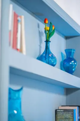 a blue vase with a flower in it on a shelf at Belvedere Suite in Termini Imerese