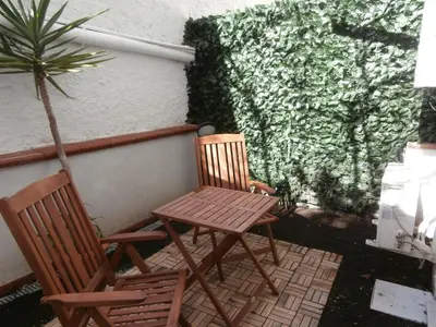 two chairs and a table on a patio with a plant at Busalacchi B&B in Mondello