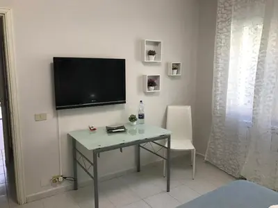 a room with a table and a television on a wall at Busalacchi B&B in Mondello